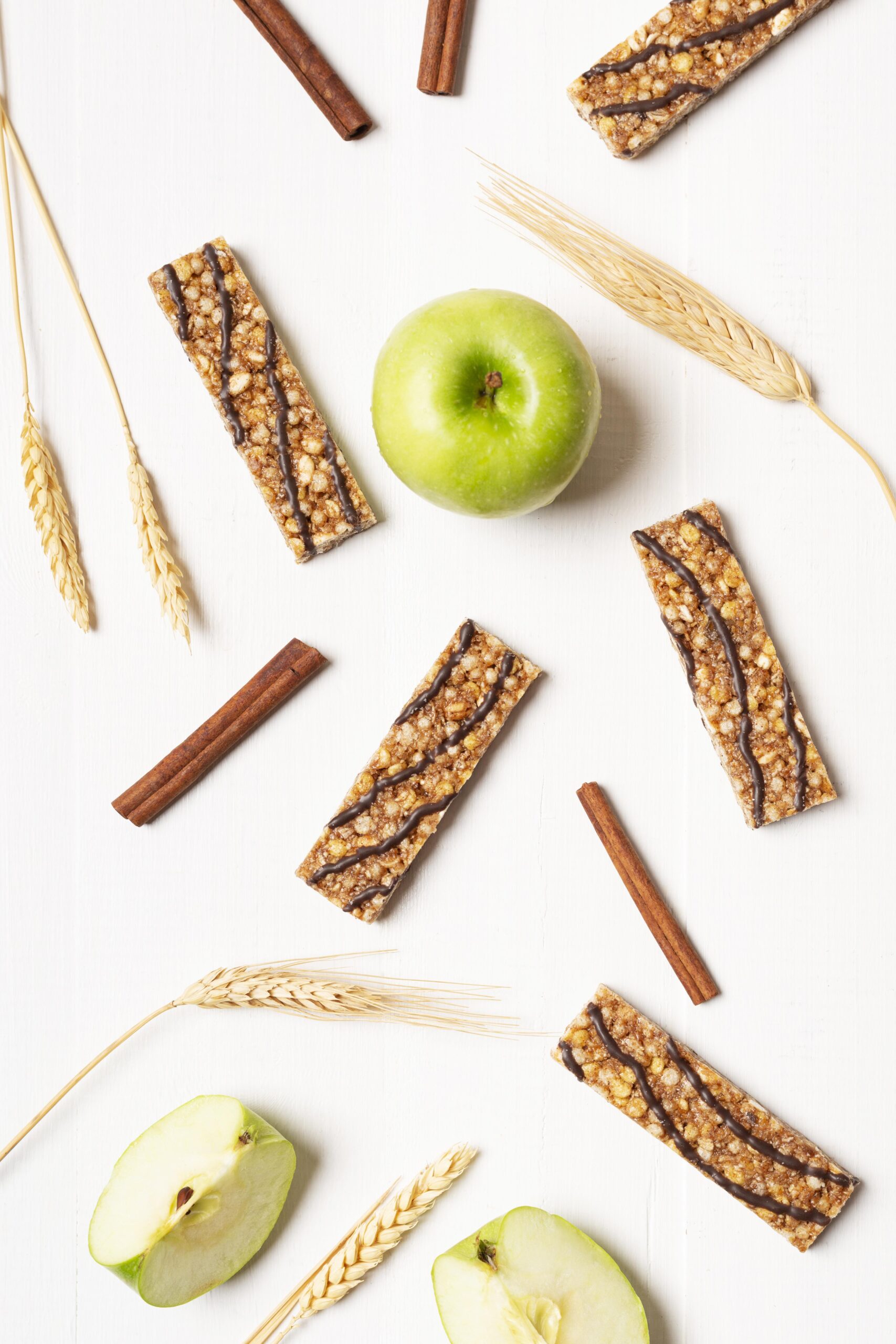 Zdrowe batony musli z dodatkiem czekolady na tle zielonych jabłek